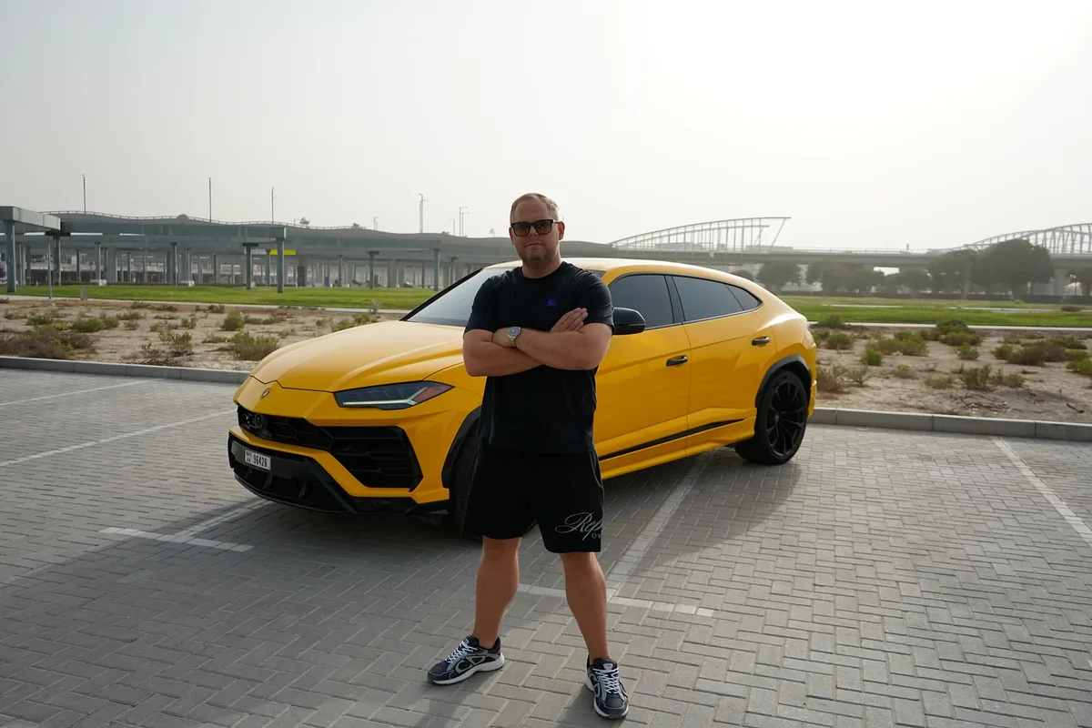 Damien Pearl, marketing mentor and multi-brand founder, standing in front of a yellow Lamborghini Urus in Dubai